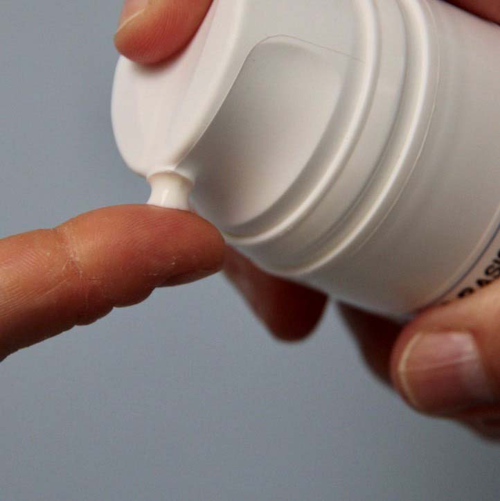 Photo of a bit of moisturizer that is being pressed out of a tube onto a finger